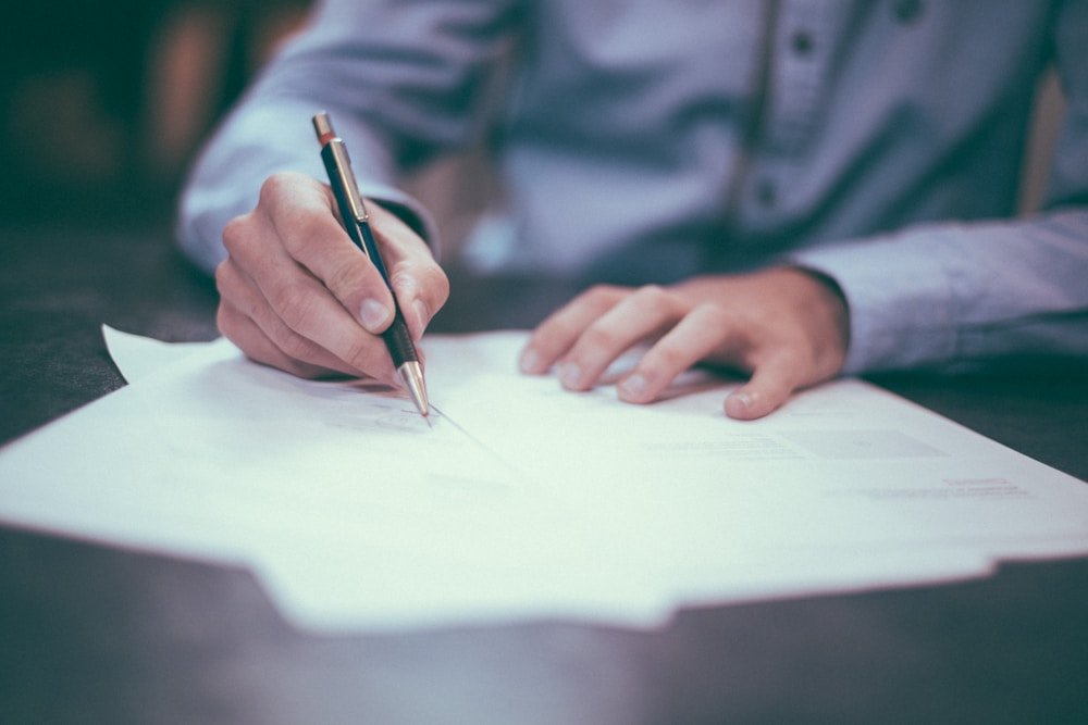 A person reviewing and taking notes on insurance paperwork